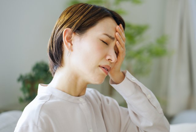 頭痛で頭をおさえる女性